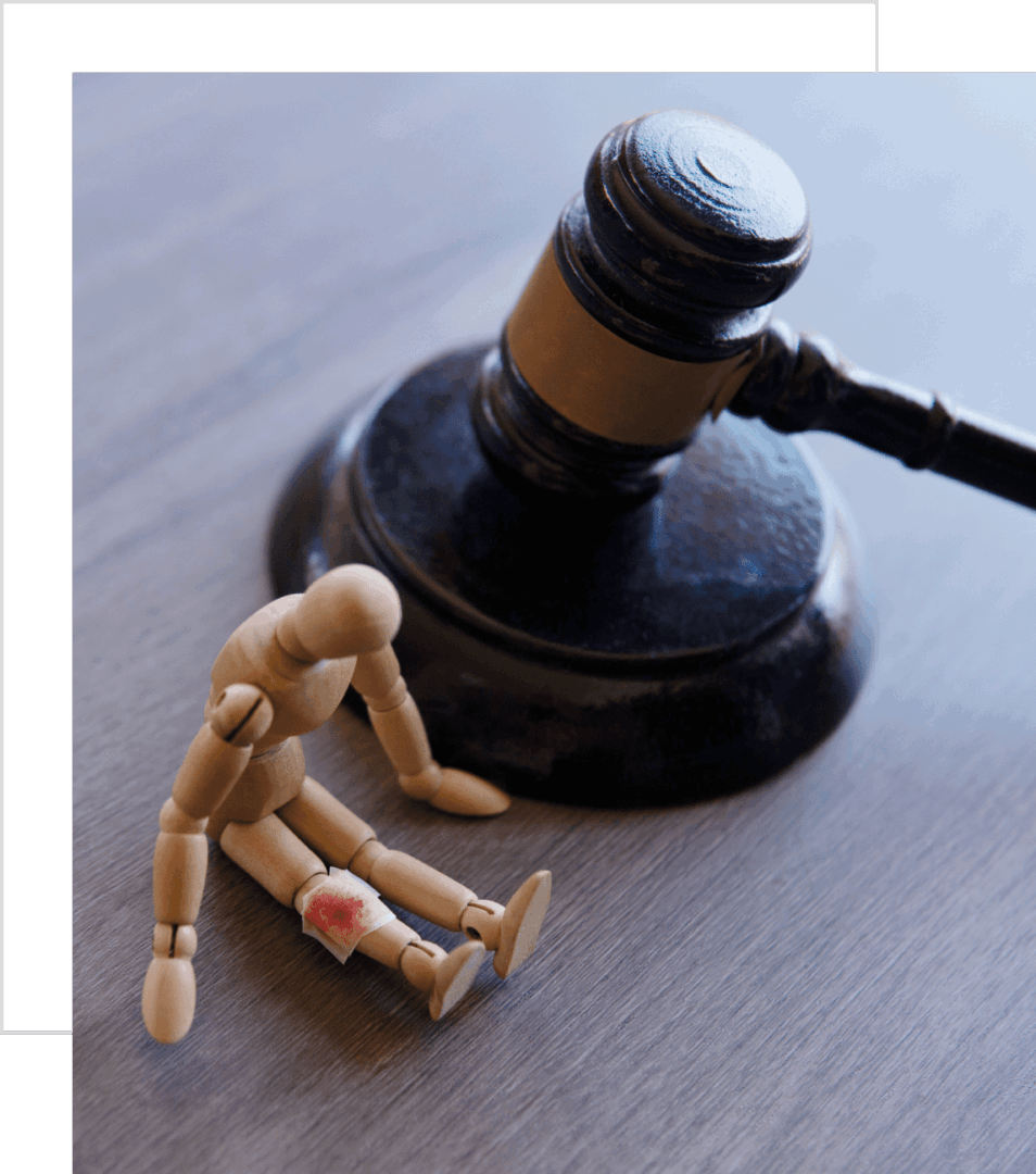 Wooden figure injured near a judge's gavel symbolizing legal harm.