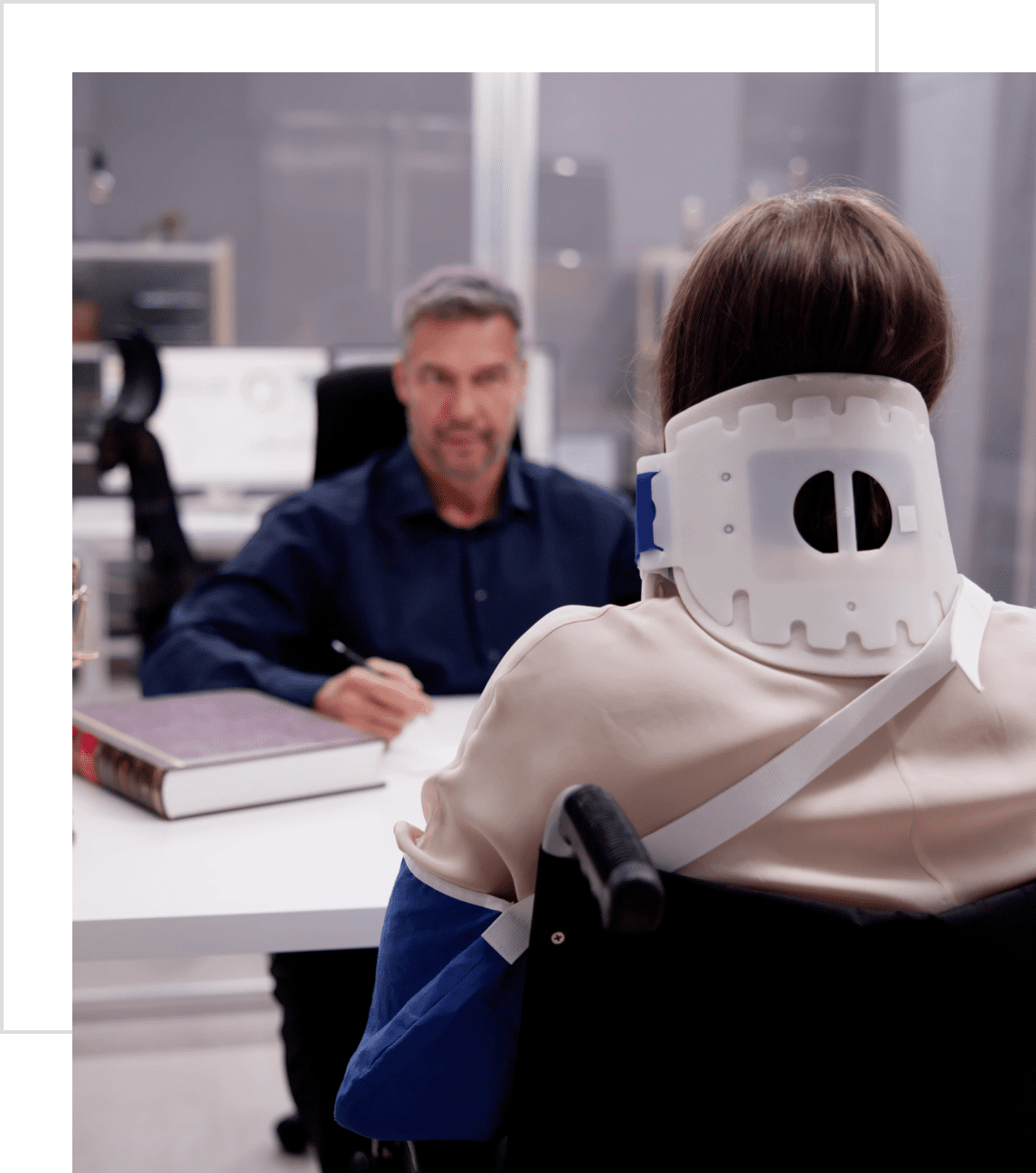 A man in a neck brace sits across from a serious man at a desk.